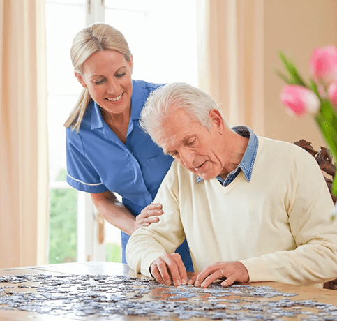 A woman helping an older man with a puzzle.