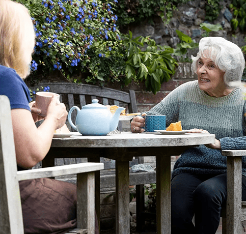 Two women sitting at a table having tea.