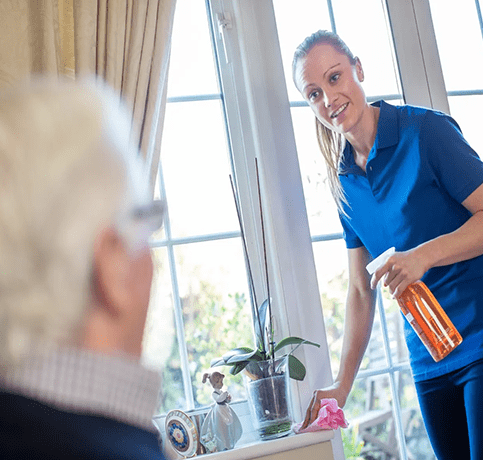 A woman in blue shirt holding spray bottle near man.