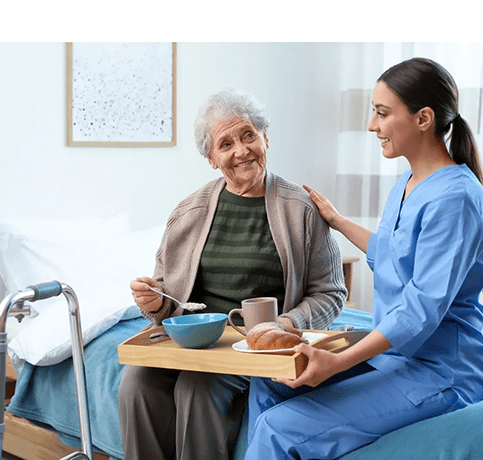 A woman sitting on the bed with an elderly person.