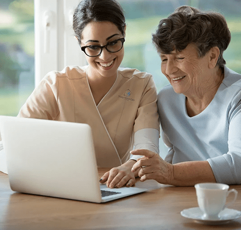 A woman and an older lady are looking at a laptop.