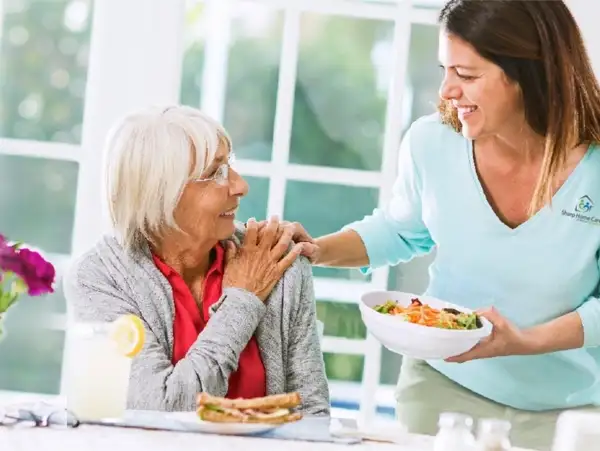 A woman is feeding something to an older lady.