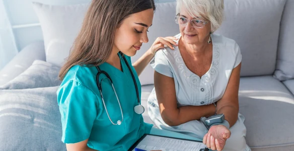 A nurse and an older woman are looking at papers.