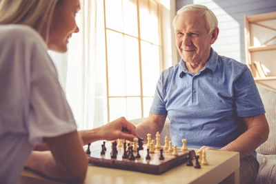 A man and woman playing chess on the table.