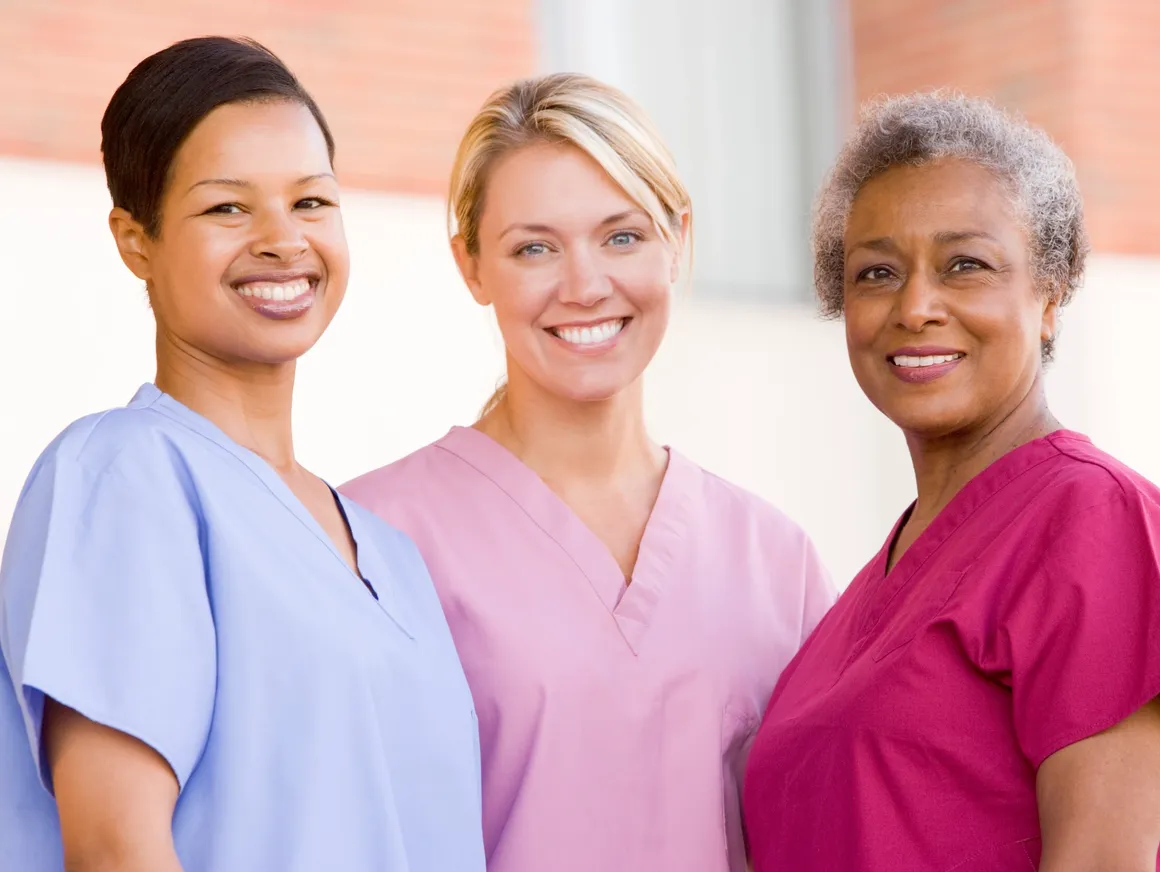 Three women in scrubs smiling for a picture.