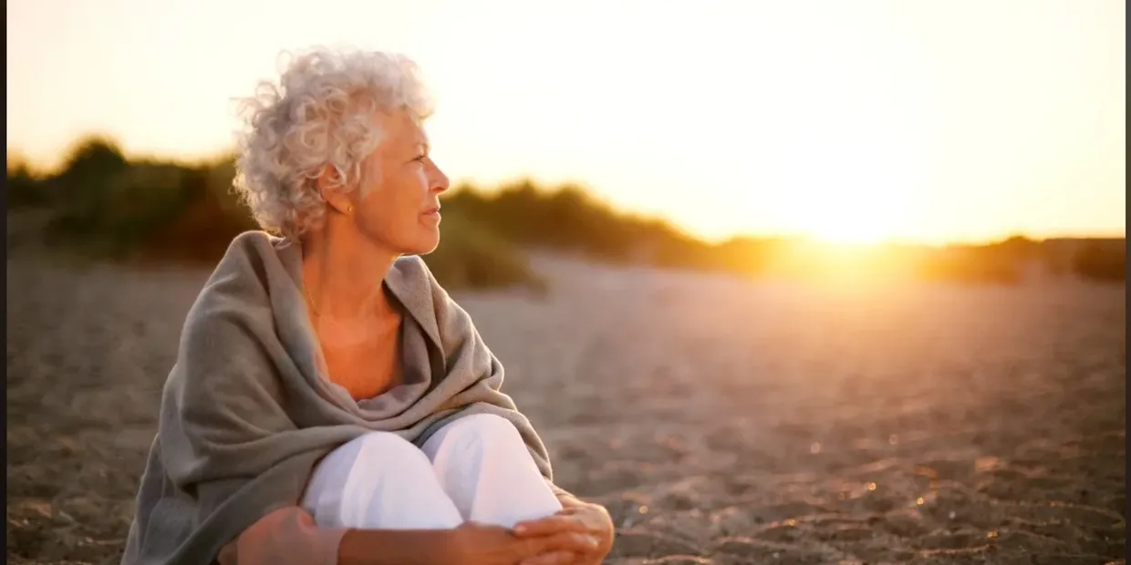 A woman sitting on the beach with her hands crossed.