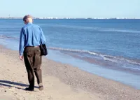 A man walking on the beach with his bag