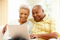 A man and woman sitting in front of a laptop.