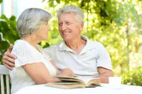 A man and woman sitting at the table with an open book.