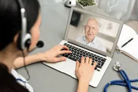 A person on the computer with an older man.