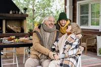 A man and two women sitting on the porch of a house.