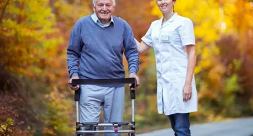 A man with a walker and a woman in white lab coat.