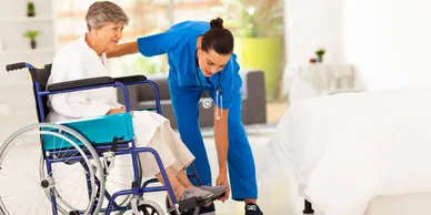 A nurse helping an elderly person in a wheelchair.