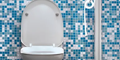 A toilet with the seat up in front of a tiled wall.