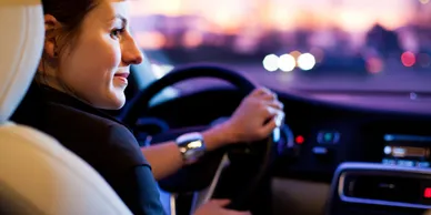 A woman sitting in her car driving at night.