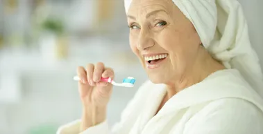 A woman in white robe holding a toothbrush.