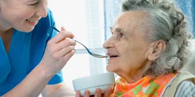 A person feeding something to an older woman