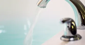 A person is washing their hands with water from the faucet.