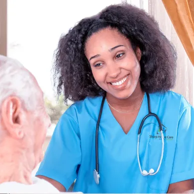 A nurse smiling at an older man in blue scrubs.