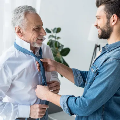 A man helping another man tie his neck tie.