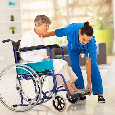 A nurse helping an elderly person in a wheelchair.