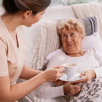 A woman holding a cup of tea next to an older lady.