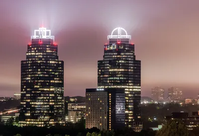 A view of two buildings with lights on them.