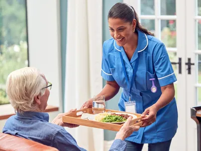 A woman serving food to an elderly person.