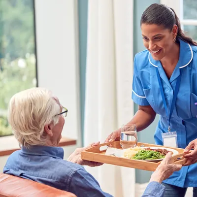 A woman serving food to an elderly person.