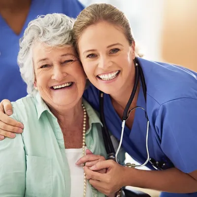 A nurse and an older woman smiling for the camera.