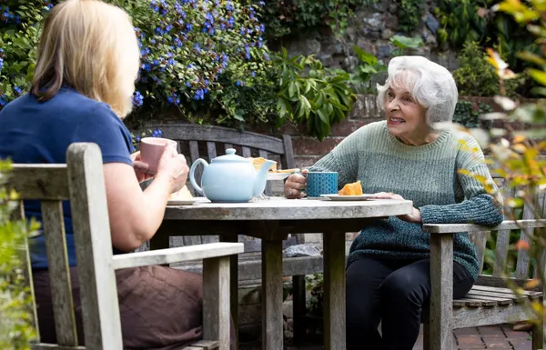 Two women sitting at a table having tea.