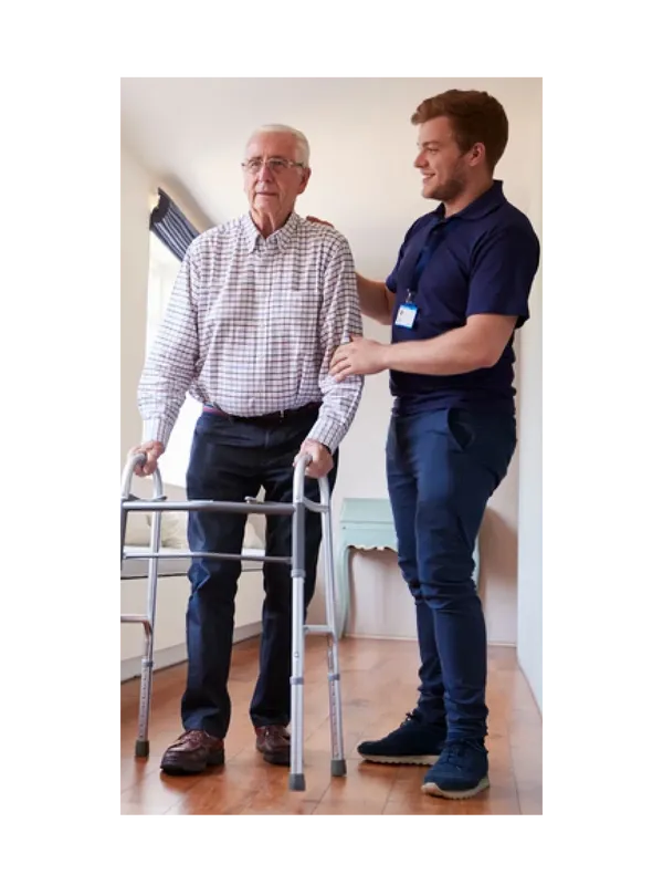 A man helping an older gentleman walk with a walker.