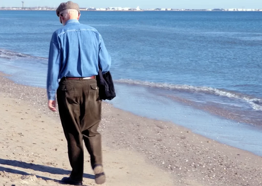 A man walking on the beach with his bag