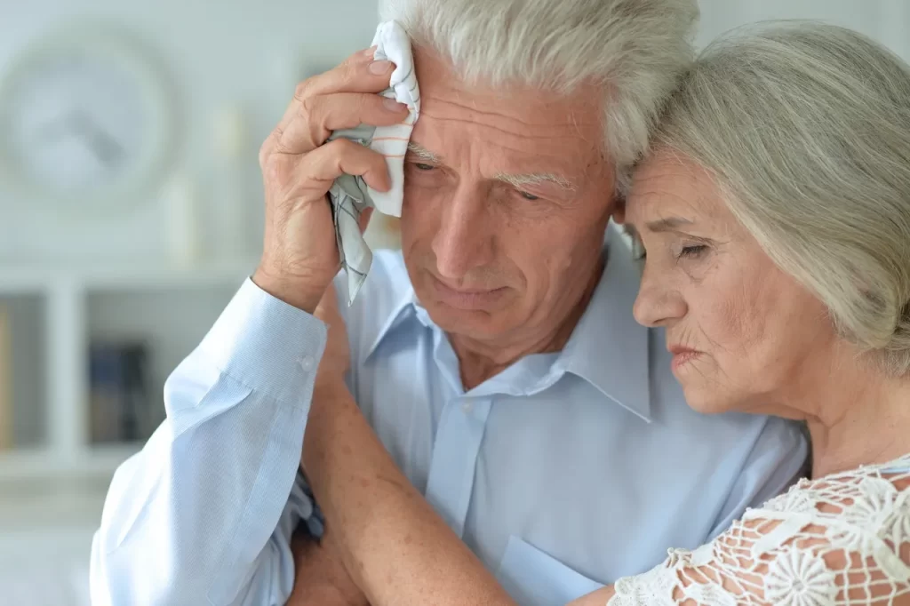 An older man and woman are looking at a cell phone.