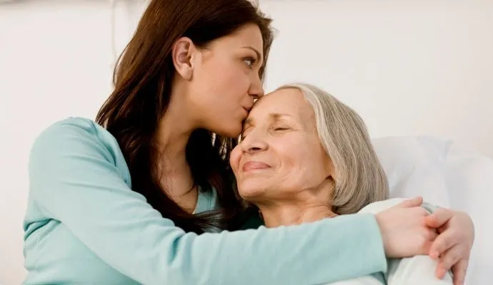 A woman kissing an older lady on the cheek.