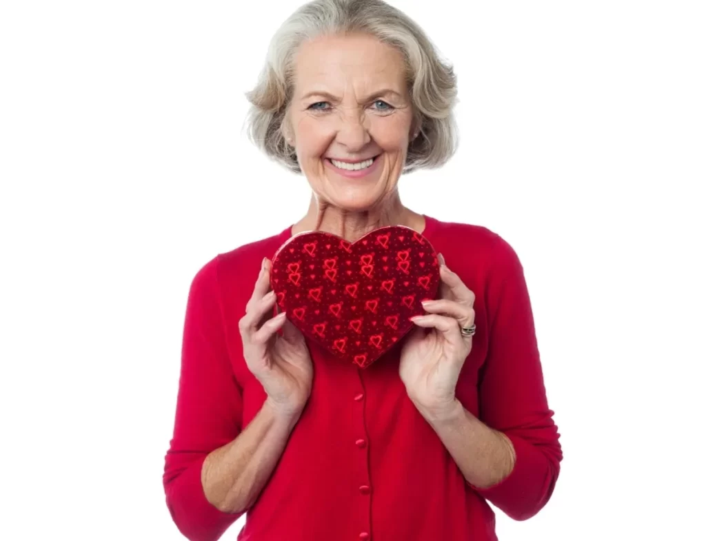 A woman holding a heart shaped pillow in her hands.