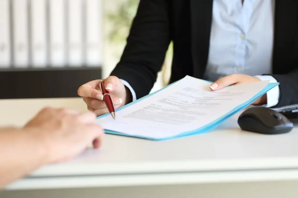 A person is signing papers on top of a table.