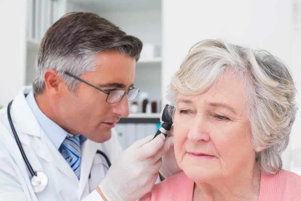 A doctor examining an older woman 's ear.