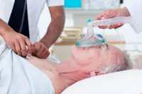 A man laying in bed with an oxygen mask on his face.